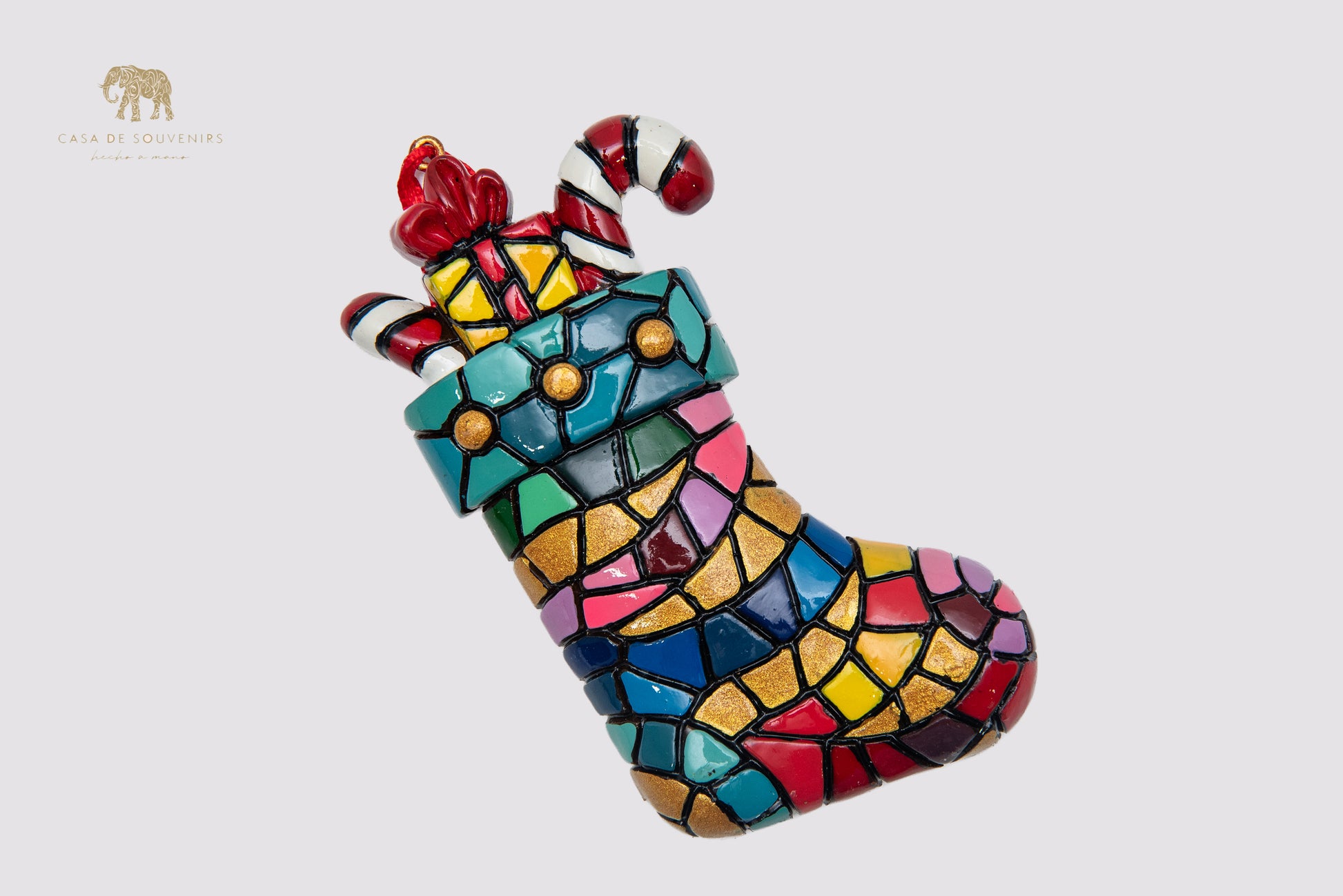 A Christmas ornament in the shape of a boot decorated with a mosaic of vibrant colors.