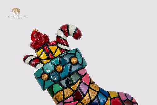 A Christmas ornament in the shape of a boot decorated with a mosaic of vibrant colors.