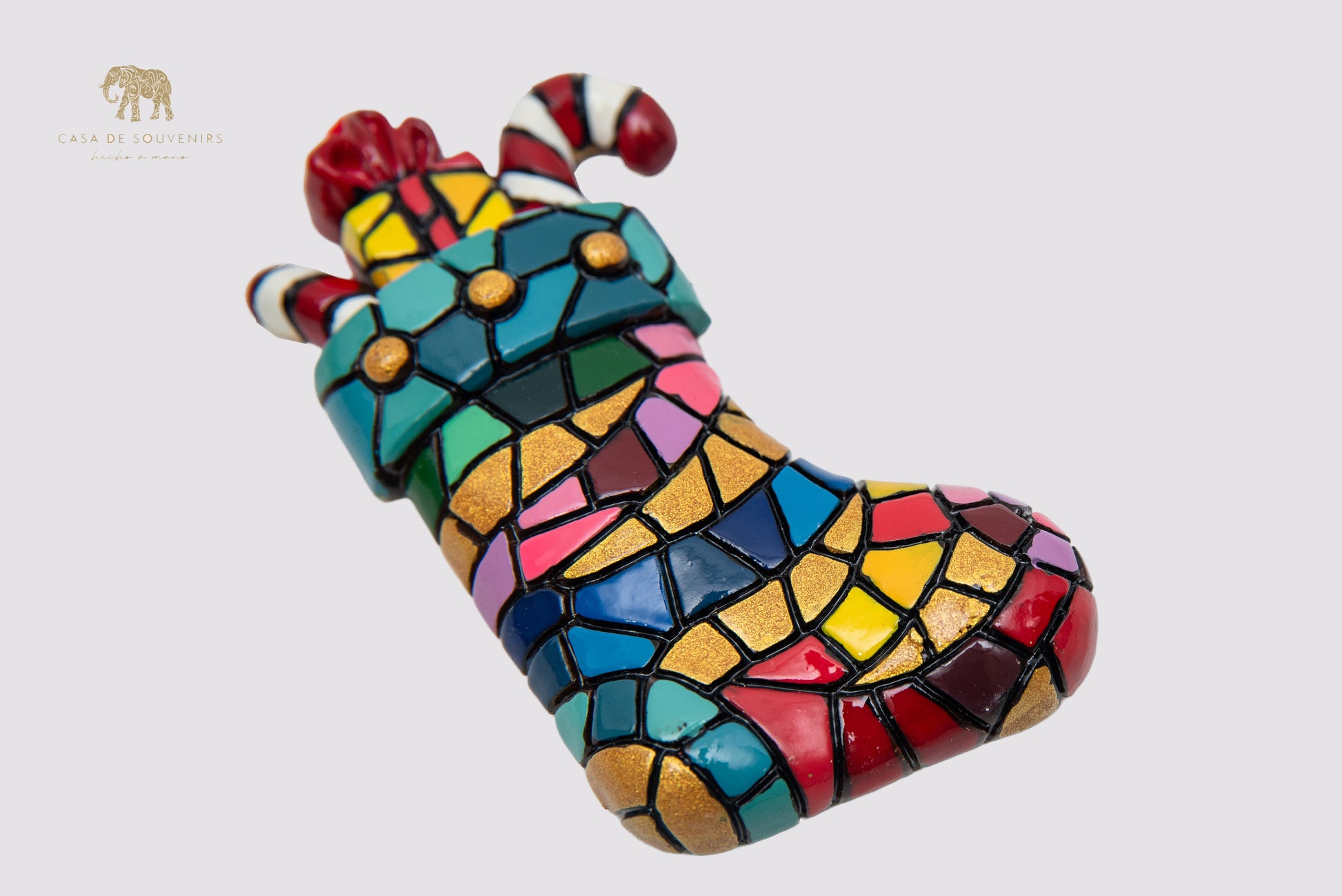 A Christmas ornament in the shape of a boot decorated with a mosaic of vibrant colors.