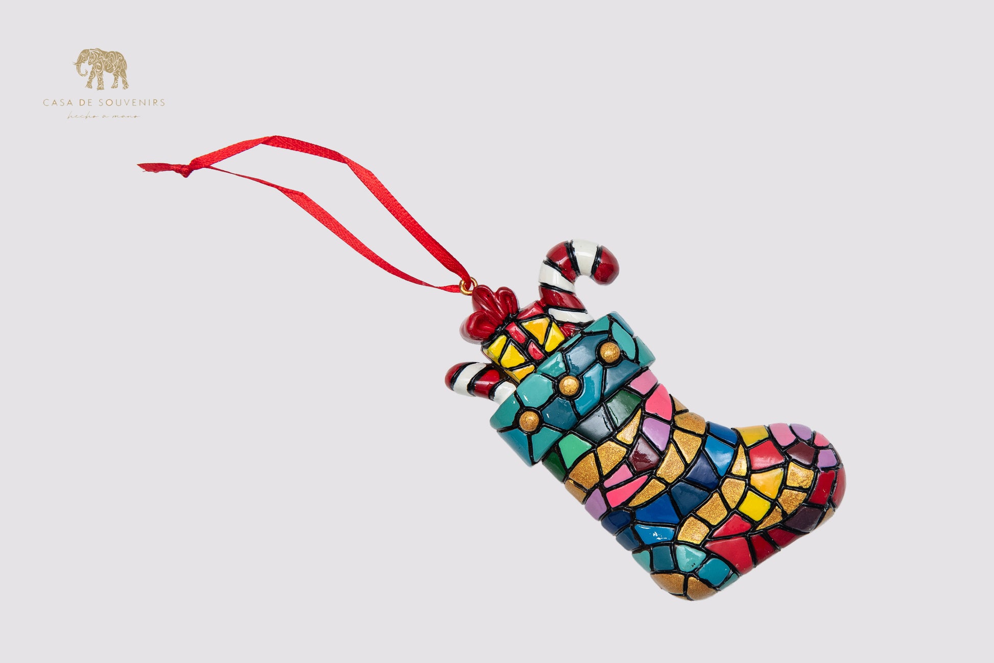 A Christmas ornament in the shape of a boot decorated with a mosaic of vibrant colors.